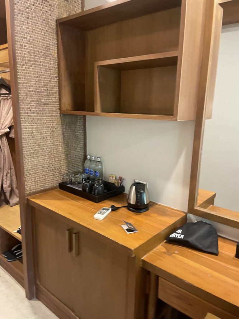 In-room coffee and tea station with kettle, cups, and complimentary bottled water