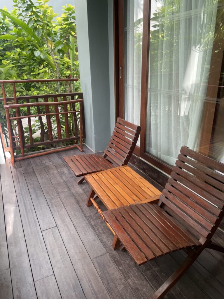 Private terrace with wooden chairs and table a few steps from the pool in a Pool-Access room