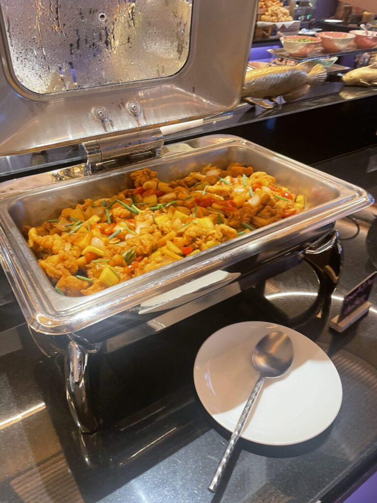 Buffet pan of bite-size chicken with peppers and onions in orange sauce