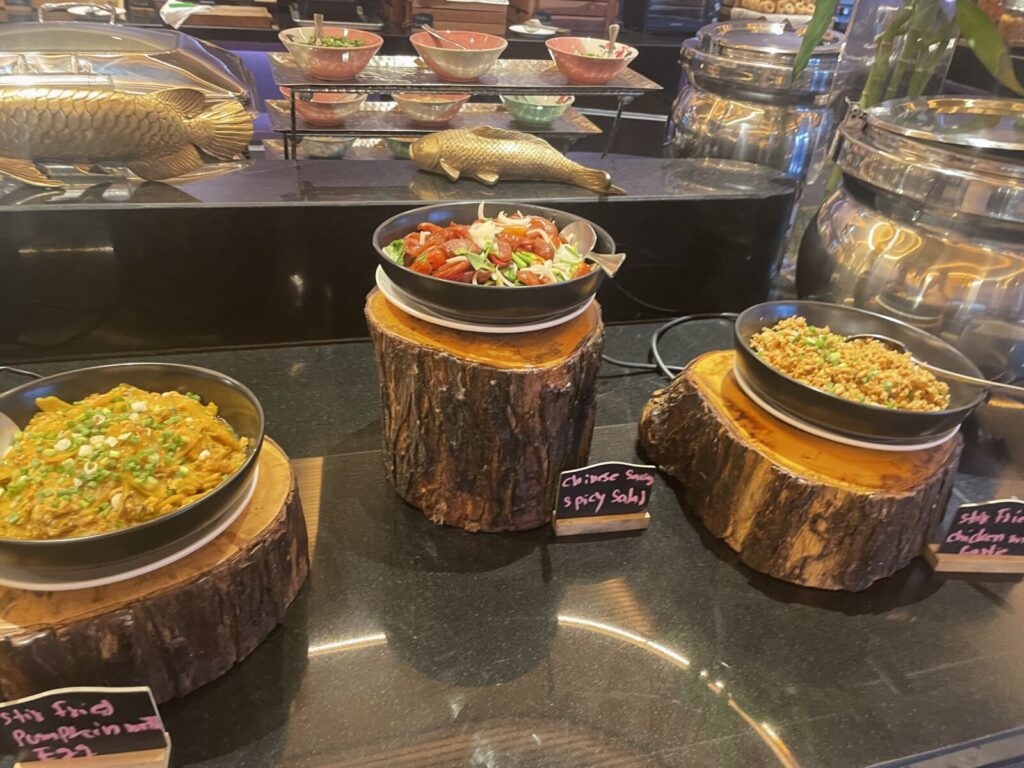 Three bowls on wood stands with pumpkin stir-fry, spicy salad, and fried rice side.