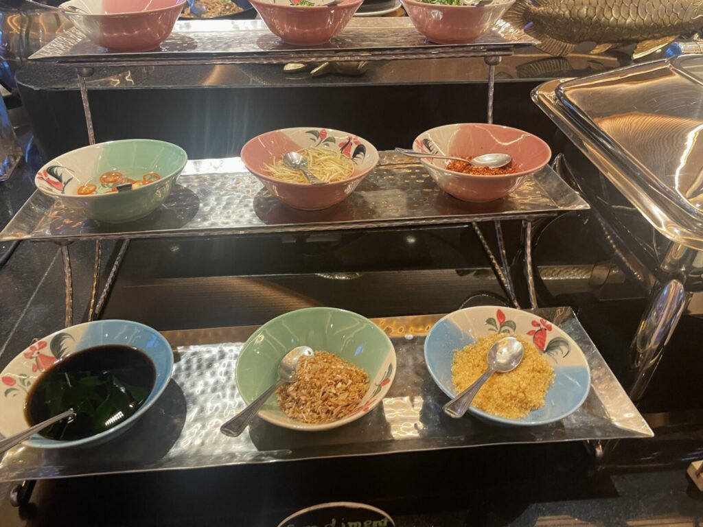 Bowls of sliced chilies, shredded ginger, chili flakes, soy sauce, and crispy toppings.