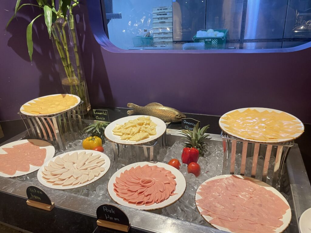 Plates of chicken and pork ham with Emmental and American cheese slices.