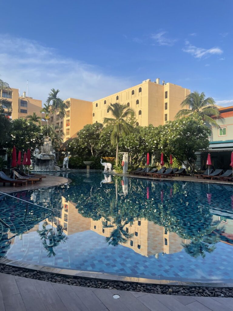 Main pool at sunrise with palm reflections and clear blue sky