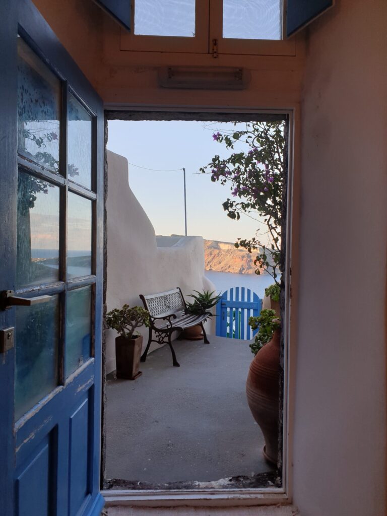 View from Anemi House doorway to terrace with blue gate and sea Santorini